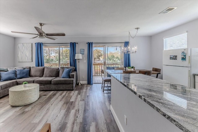 6183 Waverly Rd, Weeki Wachee, FL 34607 - living area with healthy amount of natural light, wood finished floors, a chandelier, and baseboards