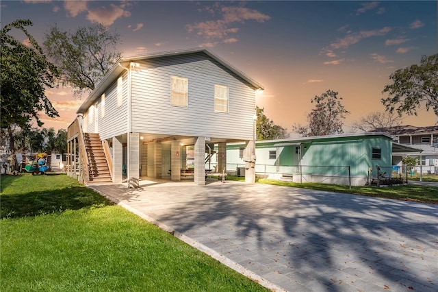 6183 Waverly Rd, Weeki Wachee, FL 34607 - rear view of house featuring a carport, stairway, driveway, and a lawn