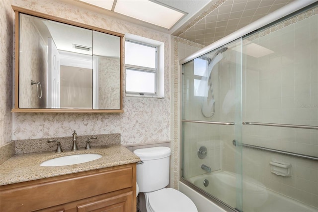 full bathroom featuring visible vents, toilet, shower / bath combination with glass door, wallpapered walls, and vanity