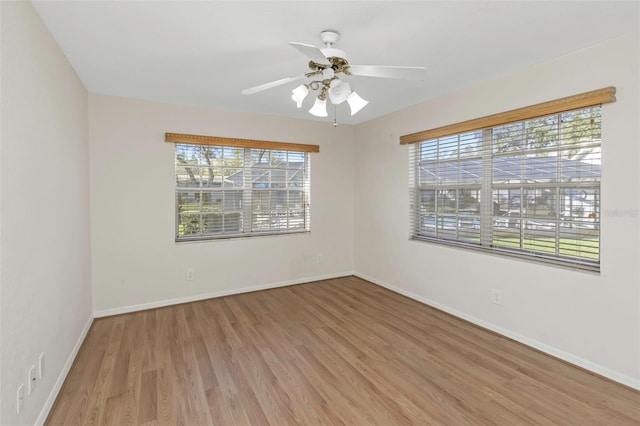 empty room featuring baseboards, light wood finished floors, and ceiling fan