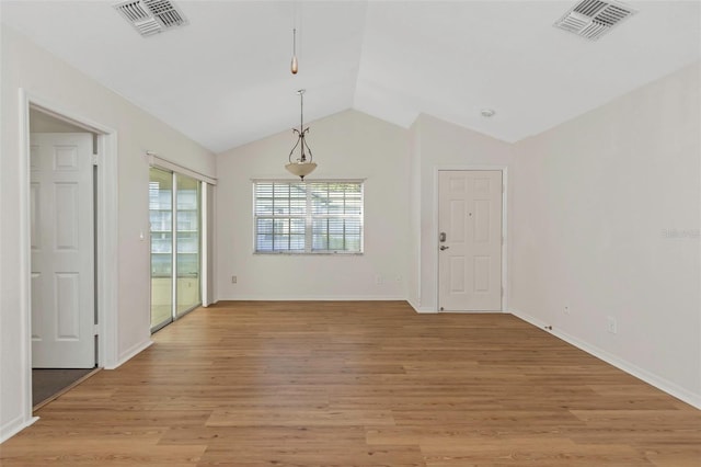 unfurnished dining area featuring visible vents, baseboards, light wood-style floors, and vaulted ceiling