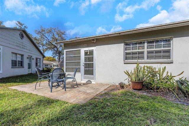 back of property featuring a yard, stucco siding, and a patio