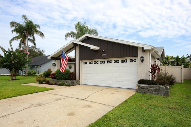 mid-century modern home with an attached garage, concrete driveway, a front yard, and fence