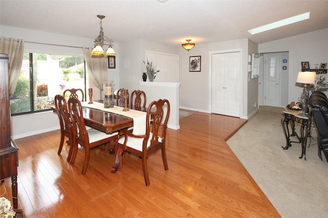 dining space with light wood-style floors and a textured ceiling