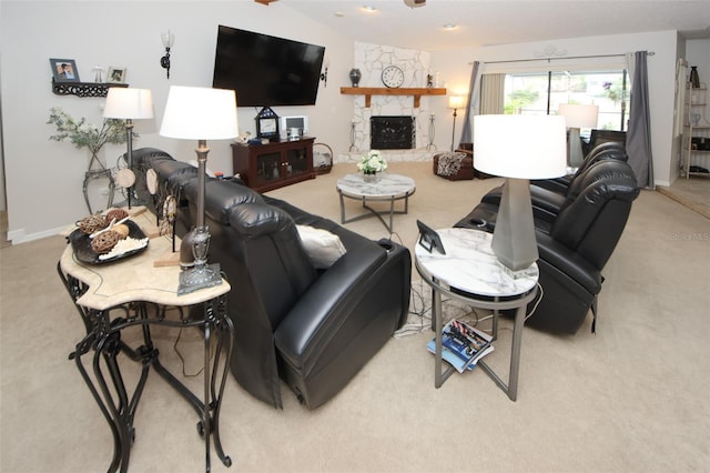 carpeted living area featuring baseboards and a stone fireplace