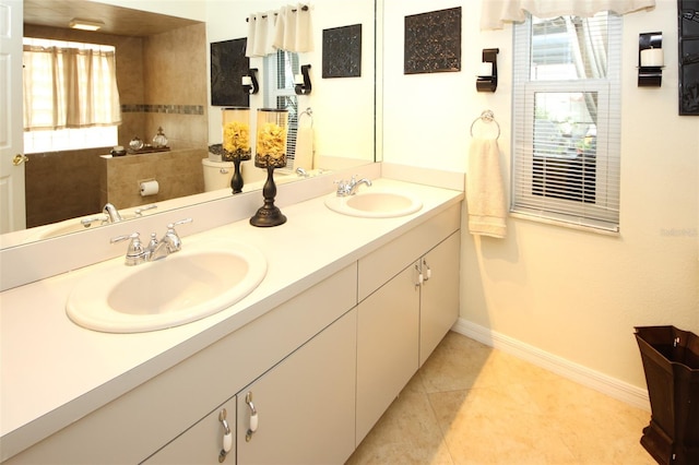 bathroom featuring toilet, double vanity, baseboards, and a sink