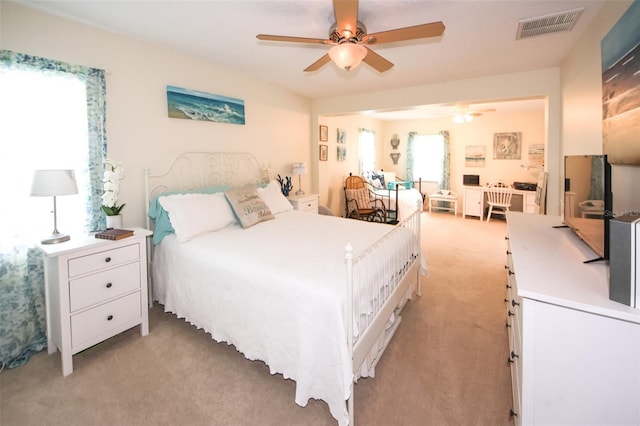 bedroom featuring a ceiling fan, visible vents, and light colored carpet