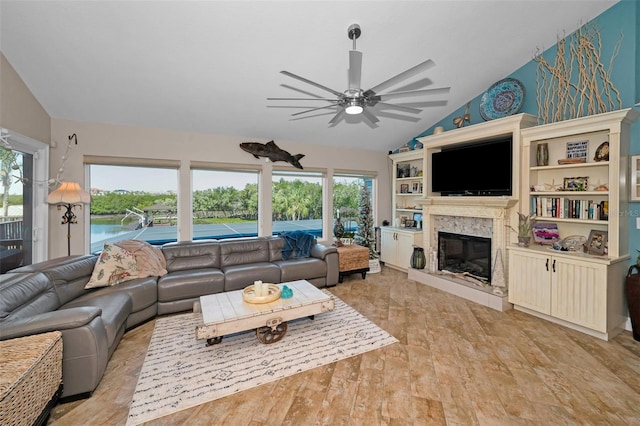 living room with lofted ceiling, ceiling fan, a wealth of natural light, and a high end fireplace