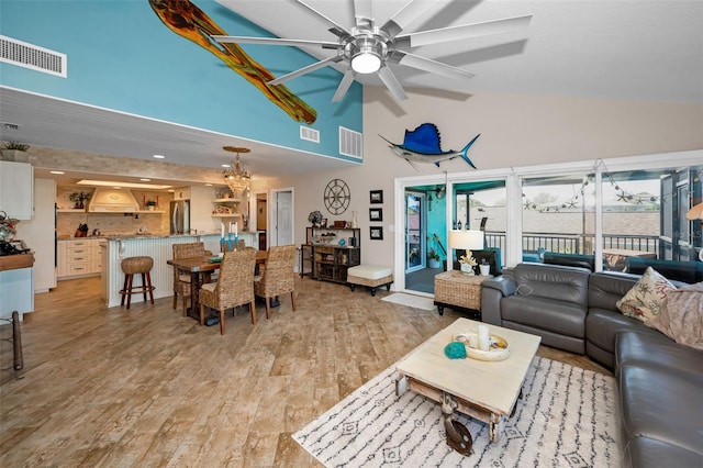 living room featuring lofted ceiling, light wood finished floors, and visible vents