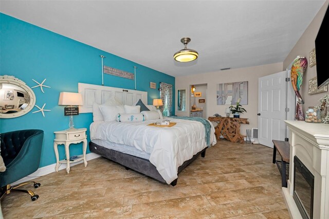 bedroom featuring baseboards and a glass covered fireplace