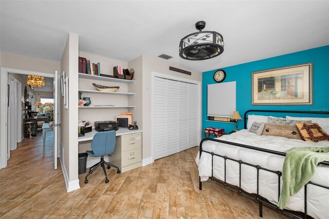 bedroom with light wood-type flooring, visible vents, and a closet