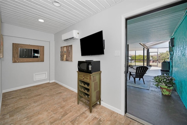 living area with a sunroom, a wall unit AC, baseboards, and light wood finished floors