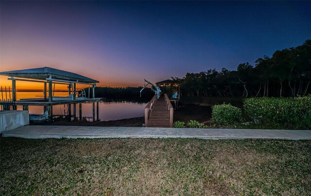 view of dock with a water view, boat lift, and a lawn