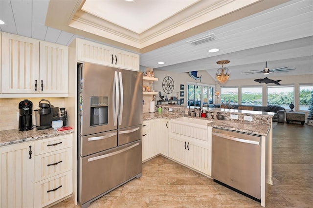 kitchen featuring stainless steel appliances, visible vents, open floor plan, a sink, and a peninsula