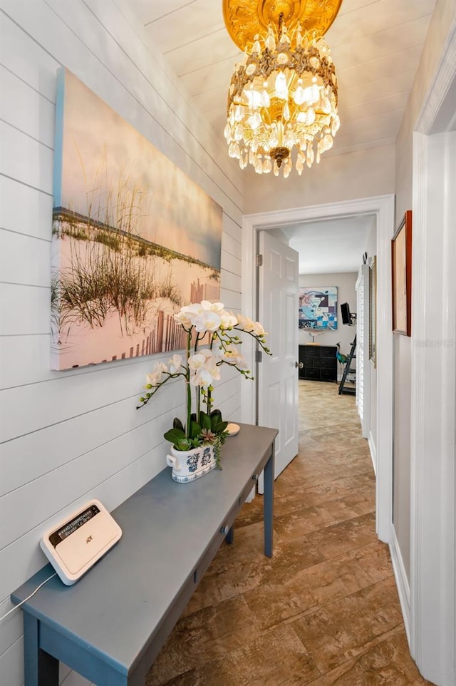 corridor featuring wooden walls and an inviting chandelier