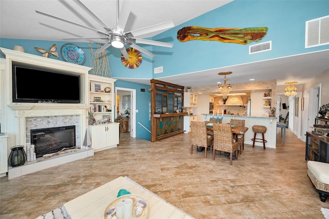 living room featuring high vaulted ceiling, a high end fireplace, visible vents, and ceiling fan