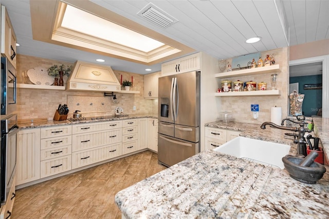 kitchen featuring a raised ceiling, stainless steel fridge, premium range hood, and open shelves