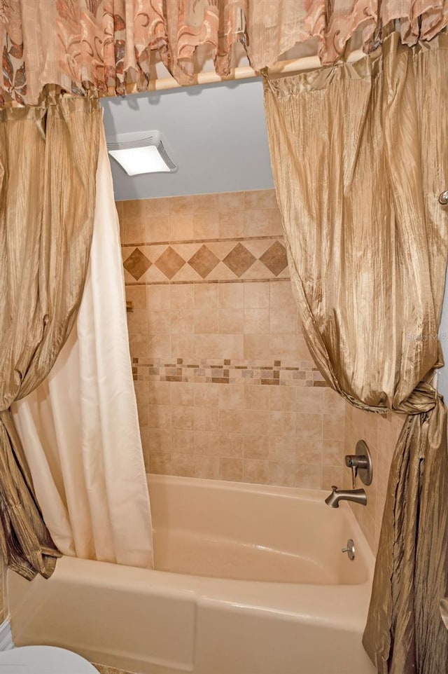 bathroom featuring toilet and shower / tub combo with curtain