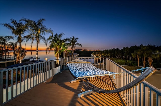 deck at dusk featuring a water view