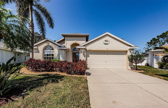 ranch-style house featuring stucco siding, a front yard, concrete driveway, and an attached garage