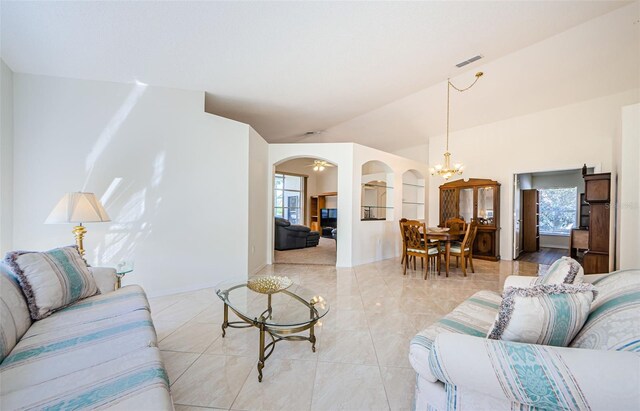 living room with a wealth of natural light, visible vents, arched walkways, lofted ceiling, and a chandelier