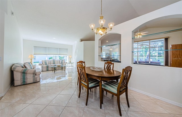 dining area featuring light tile patterned flooring, ceiling fan with notable chandelier, arched walkways, and baseboards