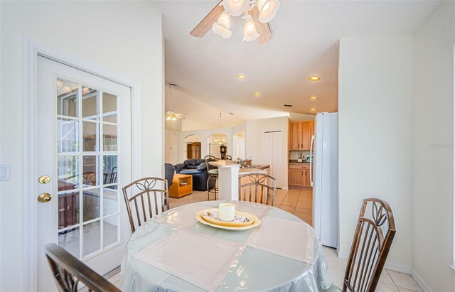 dining room featuring light tile patterned floors, arched walkways, ceiling fan, and vaulted ceiling