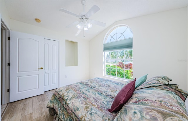 bedroom with a closet, light wood-style flooring, ceiling fan, and vaulted ceiling