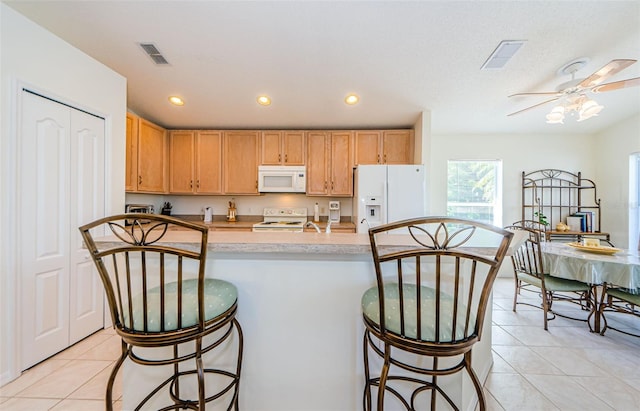 kitchen featuring a breakfast bar, recessed lighting, white appliances, light tile patterned flooring, and ceiling fan