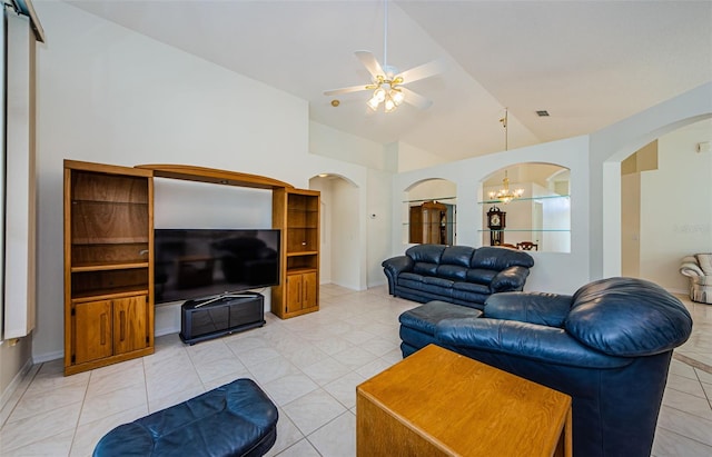 living room featuring lofted ceiling, ceiling fan with notable chandelier, arched walkways, light tile patterned flooring, and baseboards