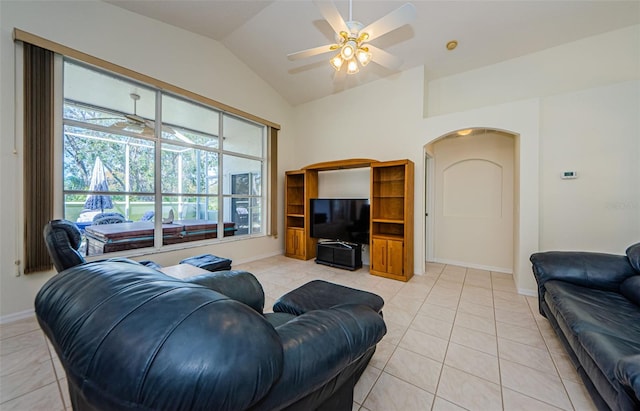 living area with baseboards, lofted ceiling, light tile patterned floors, arched walkways, and a ceiling fan