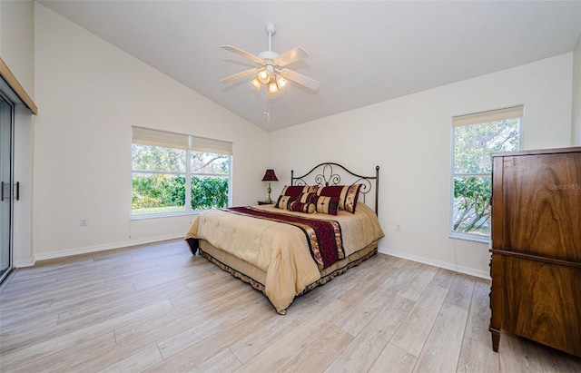 bedroom featuring light wood finished floors, multiple windows, baseboards, and lofted ceiling