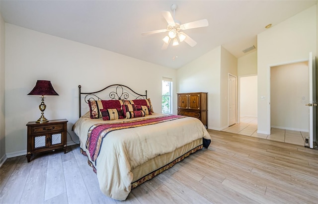 bedroom featuring visible vents, light wood-style flooring, baseboards, ceiling fan, and vaulted ceiling