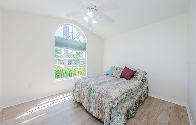 bedroom with a ceiling fan, vaulted ceiling, wood finished floors, and baseboards