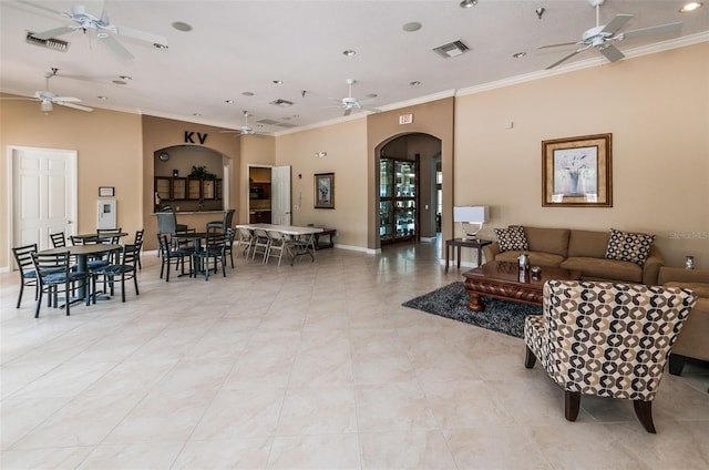 living room with crown molding, visible vents, arched walkways, and ceiling fan