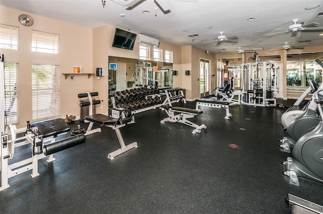 gym with visible vents, plenty of natural light, a ceiling fan, and a wall unit AC