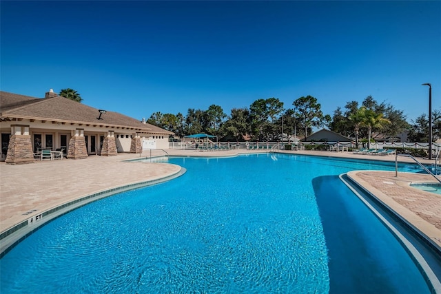 community pool with french doors, fence, and a patio area