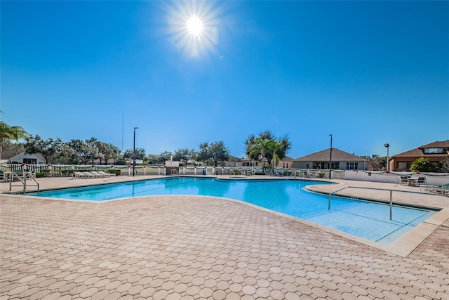 community pool with a patio and fence