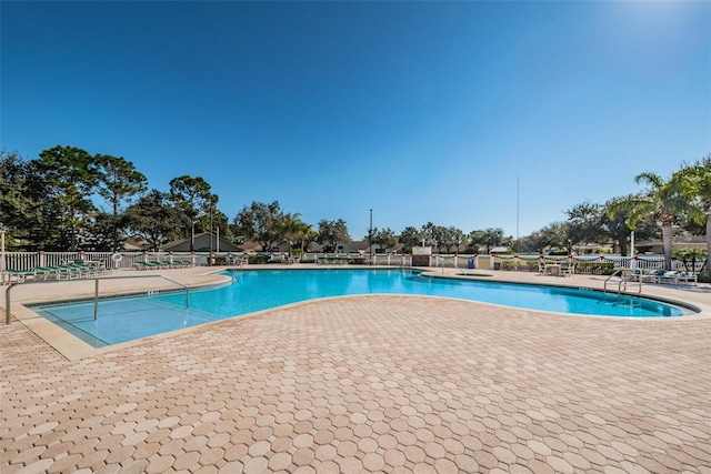 pool with a patio area and fence