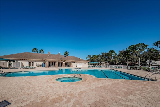 pool featuring a community hot tub, a patio, and fence