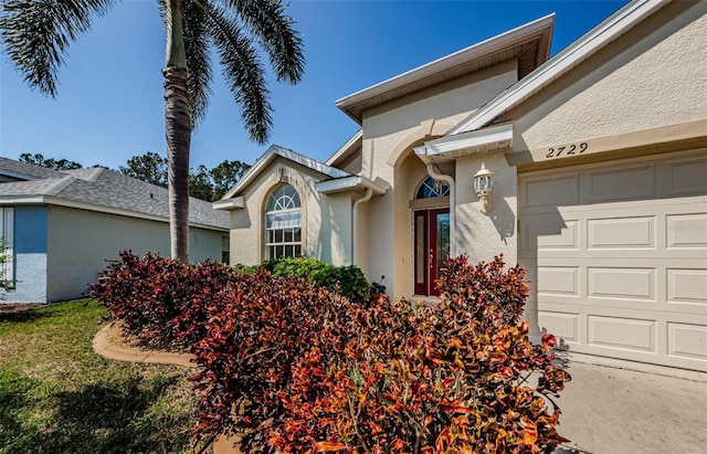 view of exterior entry featuring stucco siding and an attached garage