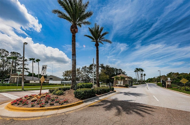 view of road featuring a gated entry, curbs, and street lighting