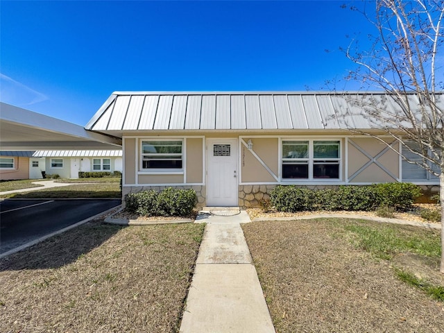 view of front of home with stone siding, a standing seam roof, metal roof, and stucco siding