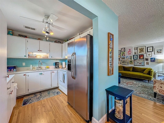 kitchen with light countertops, white electric range, visible vents, a sink, and stainless steel fridge