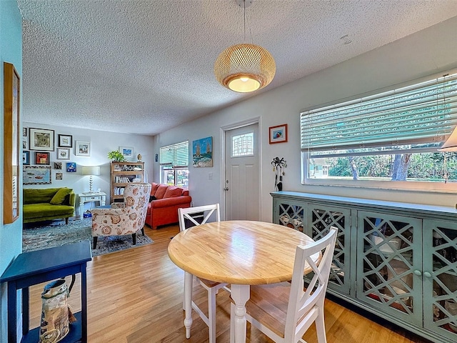 dining area featuring light wood-style floors and a textured ceiling