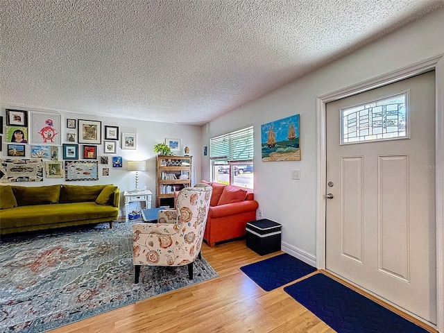 foyer with light wood finished floors, baseboards, and a textured ceiling