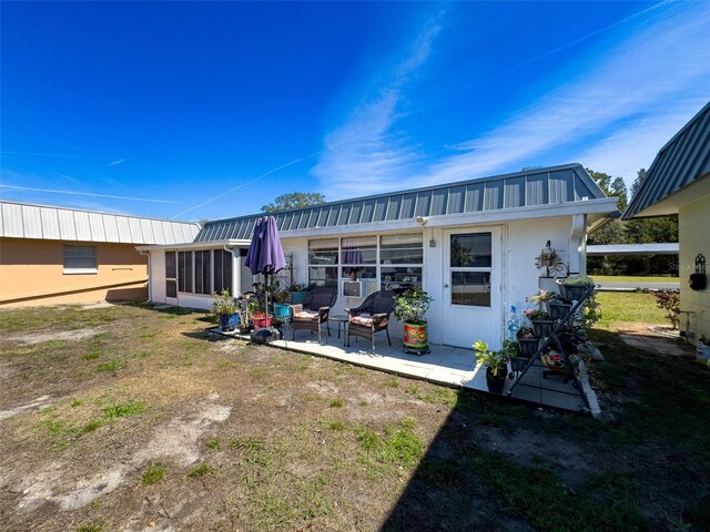 rear view of house with a patio area, metal roof, and a sunroom