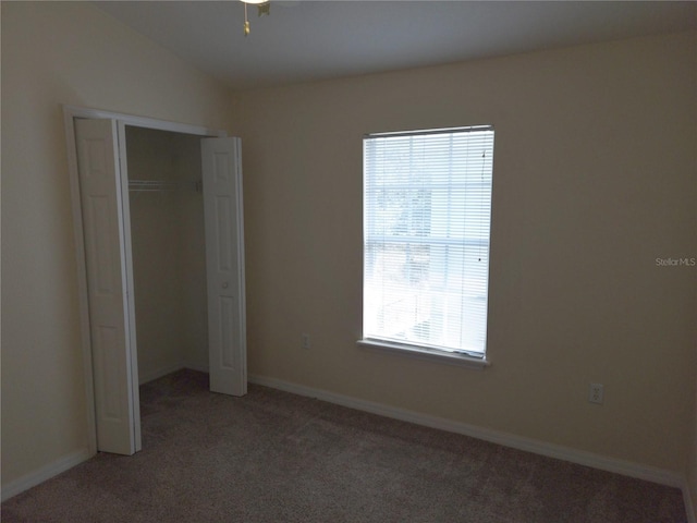 unfurnished bedroom featuring a closet, light colored carpet, vaulted ceiling, and baseboards