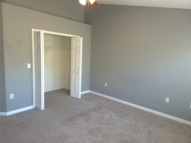 unfurnished bedroom with vaulted ceiling, a closet, carpet flooring, and baseboards