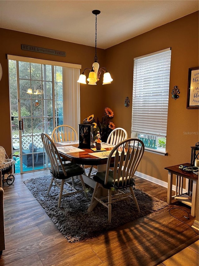 dining space featuring baseboards, a notable chandelier, and wood finished floors